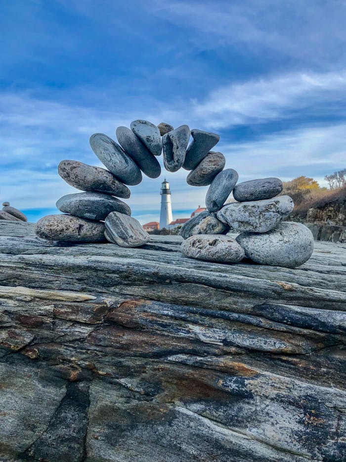Crafting Captivating Headlines: Your awesome post title goes here A serene image of balanced stones with the iconic Portland Head Lighthouse in the background.