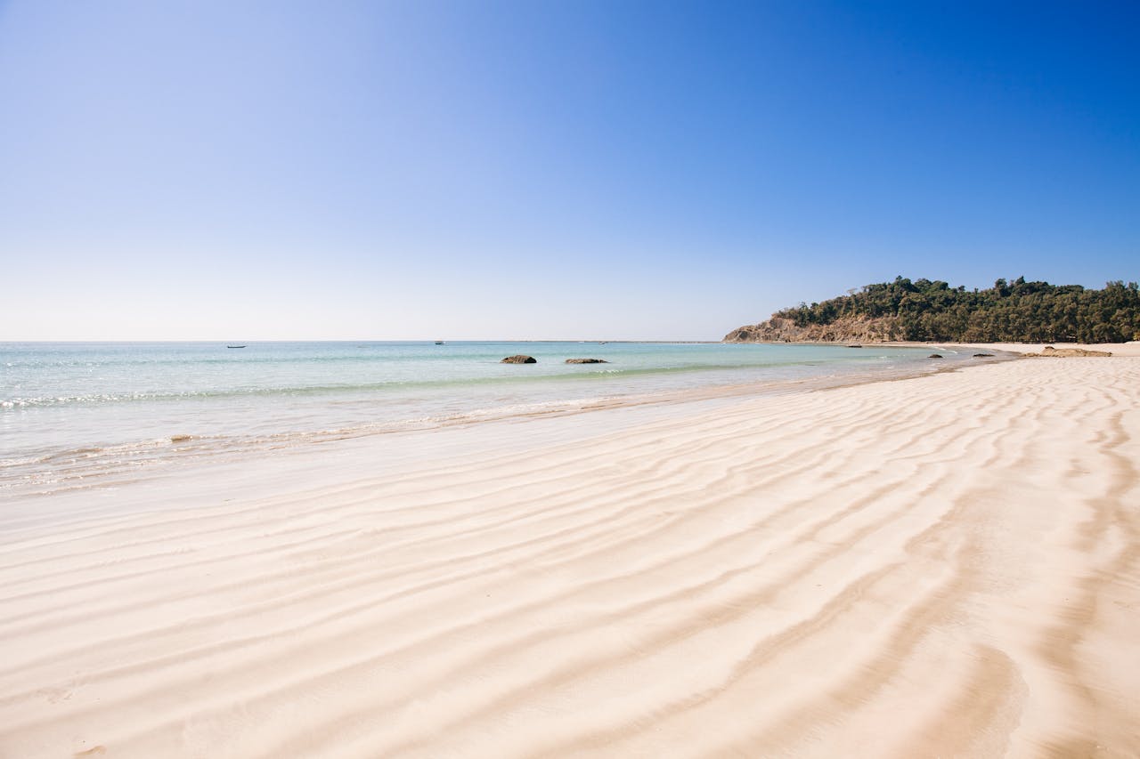 hero-img-01 A serene view of a tranquil beach with clear ocean waters and soft sand in Myanmar.